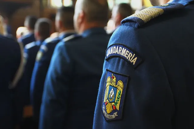 Sorakozó jandarmériai (csendőrségi) egyenruhások közeli képe, a legelöl álló katona vállán jól látható a „JANDARMERIA” felirat és Románia címere.