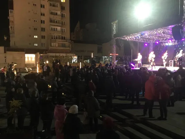 Esti szabadtéri rendezvény színpaddal, ahol zenészek lépnek fel lila és fehér fényekben, előttük nagy tömeg gyűlt össze egy téren.