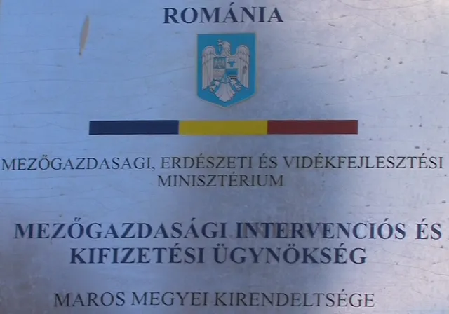 Fémtábla felirata: „ROMÁNIA” felirat és címer felett, alatta „Mezőgazdasági, Erdészeti és Vidékfejlesztési Minisztérium”, majd „Mezőgazdasági Intervenciós és Kifizetési Ügynökség”, alul „Maros megyei kirendeltsége” szöveg.