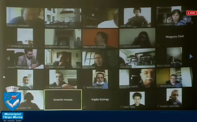 Videókonferencia-hívás képernyőképe, rácsos elrendezésben sok kis ablakban látszanak a résztvevők arcképei, nevükkel felirat alatt; bal alsó sarokban Marosvásárhely önkormányzatának logója.