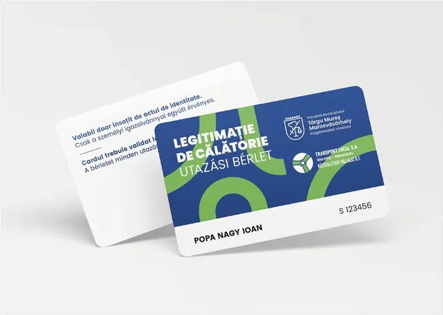 Két utazási bérletkártya látható: az elülső oldalán zöld-kék grafikai mintával, „Legitimație de călătorie – Utazási bérlet” felirattal, a Marosvásárhelyi Polgármesteri Hivatal és a Transport Local S.A. logójával, valamint egy névvel (Popa Nagy Ioan) és sorszámmal; a háttérben a kártya hátoldala látszik román és magyar nyelvű használati útmutatóval.