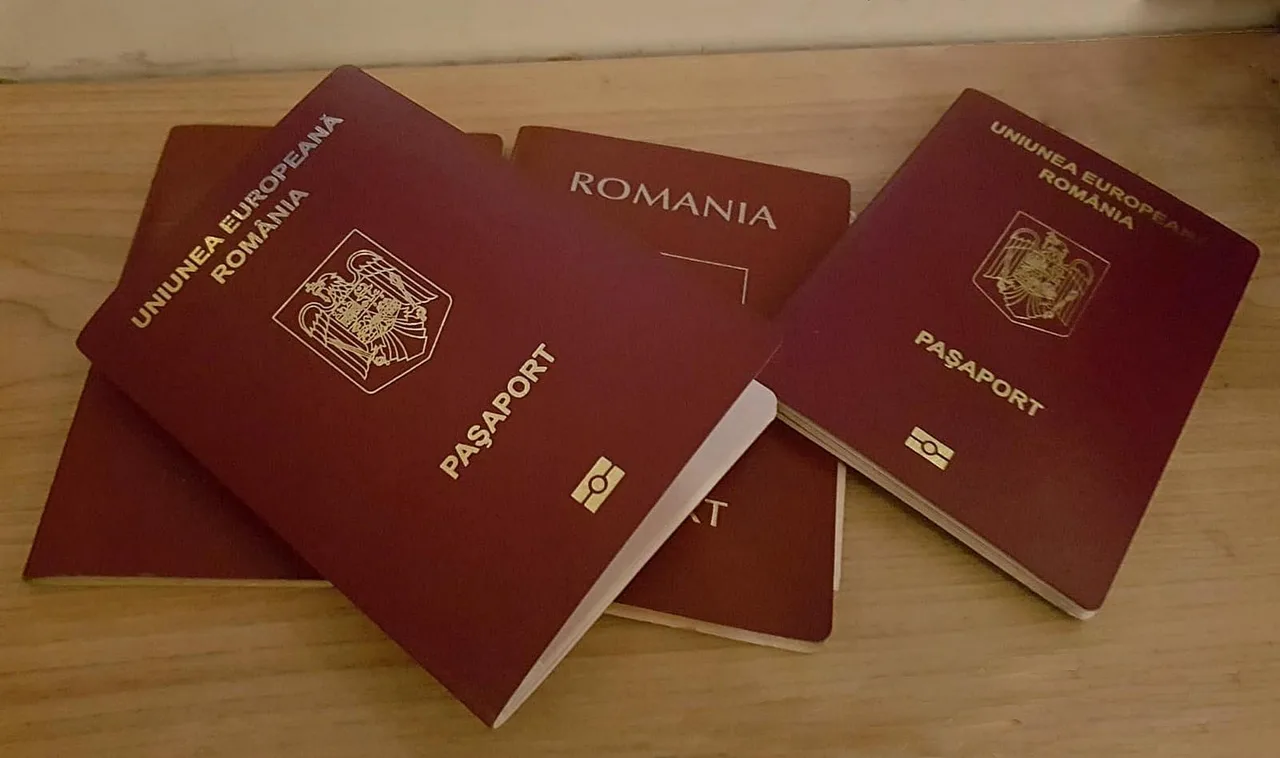 Több bordó színű román útlevél látható egymásra helyezve egy világos faasztalon, mindegyiken az „Uniunea Europeană România” felirat és a „Pașaport” szó olvasható.