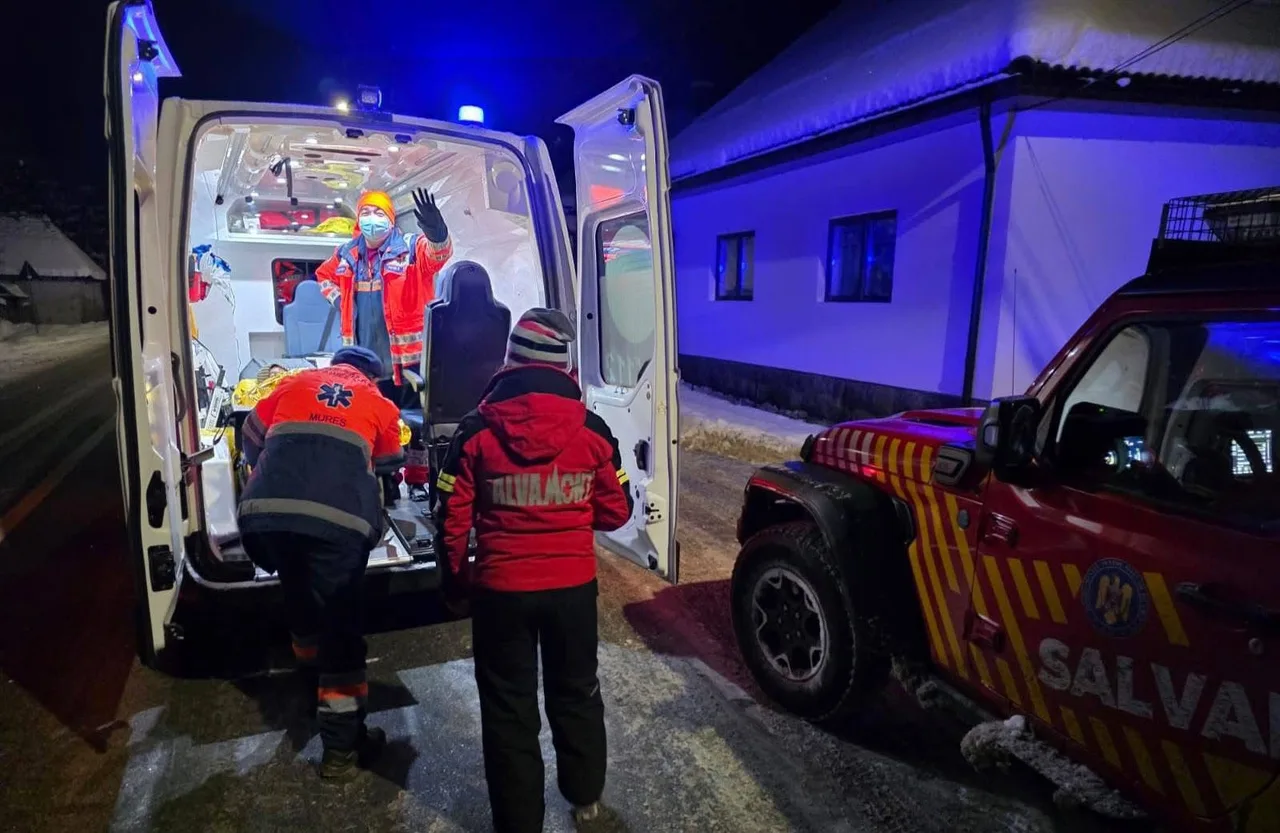 Éjszaka, havas úton mentőautó nyitott ajtajánál mentősök és hegyimentő dolgozik, egy védőmaszkos mentős integet az autó belsejéből; mellette Salvamont terepjáró áll kék és piros fényekkel.