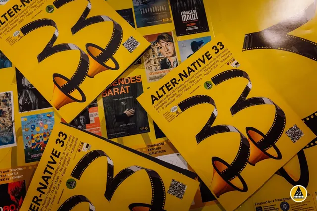 Sárga színű Alter-Native 33 rövidfilmfesztivál szórólapok és plakátok láthatók egymásra helyezve, filmszalag-motívummal és QR-kóddal, körülöttük különböző filmplakátok (Csendes Barát, Kontinental, Pădurea de Molizi, Sunyadászat).