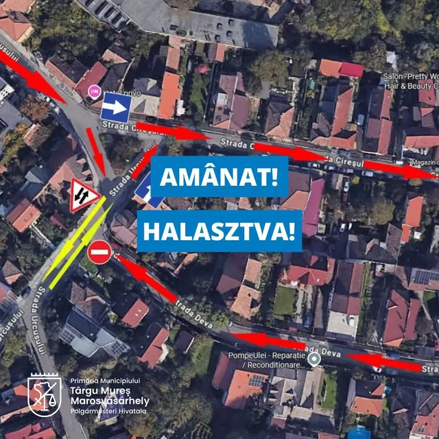 Légi felvétel Marosvásárhely egy városrészéről, piros nyilakkal jelölt tervezett forgalmi irányokkal a Cseresznyés és Dévai utcákban, valamint egytiltó jelzés az egyik útszakaszon. A képre "AMÂNAT!" és "HALASZTVA!" felirat, valamint a marosvásárhelyi polgármesteri hivatal logója van rátéve.