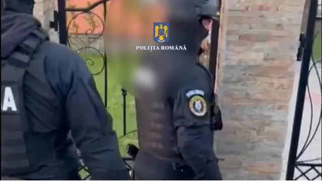 Sisakos, sötét egyenruhás rendőrök kísérnek egy kapun át egy elhomályosított arcú személyt, a felvételen a Román Rendőrség (Poliția Română) logója és felirata látszik vízjelként.