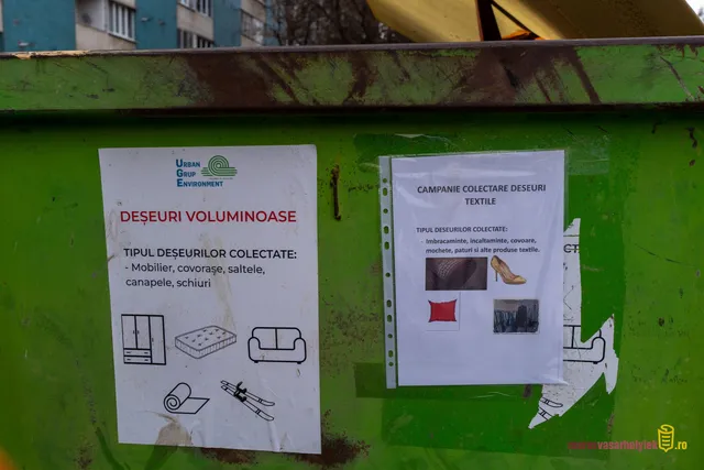 Zöld hulladékgyűjtő konténer oldalára ragasztott két tájékoztató plakát, román nyelven: az egyik a nagyméretű lomok (bútor, matrac, kanapé, szőnyeg, síléc), a másik a textilhulladék (ruha, cipő, szőnyeg, párna) gyűjtéséről szól, az Urban Grup Environment cég logójával.