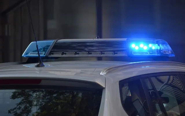 Rendőrautó tetején elhelyezett kék villogó jelzőlámpa látható közelről, éjszaka.