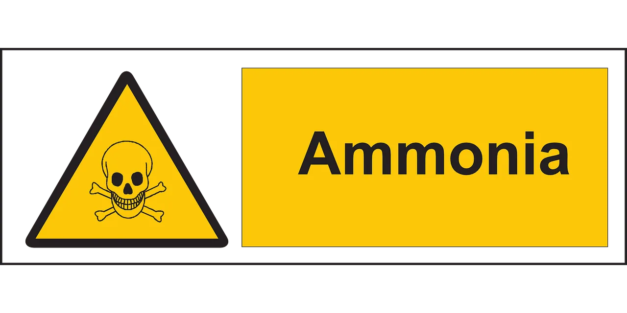 Sárga mérgező anyagra figyelmeztető tábla, koponya és lábszárcsontok szimbólummal, mellette „Ammonia” felirat.