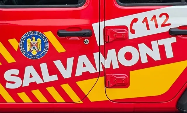 Közeli felvétel egy piros-fehér Salvamont hegyimentő gépkocsi ajtajáról, rajta a SALVAMONT felirat, a 112-es segélyhívó szám és a Belügyminisztérium Sürgősségi Helyzetek Főfelügyelőségének emblémája.
