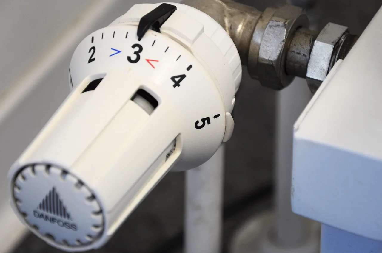 Közeli fotó egy fehér radiátor termosztátszelepről (Danfoss), amelynek forgatógombja 1-től 5-ig számozott skálával rendelkezik, a beállított érték jelenleg 3-as fokozaton áll.