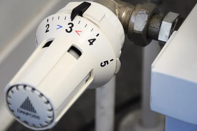 Közeli fotó egy fehér radiátor termosztátszelepről (Danfoss), amelynek forgatógombja 1-től 5-ig számozott skálával rendelkezik, a beállított érték jelenleg 3-as fokozaton áll.