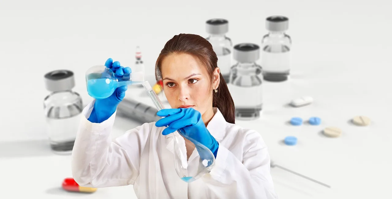 Fehér köpenyt és kék gumikesztyűt viselő nő laboratóriumi lombikból kék folyadékot tölt egy kémcsőbe, háttérben elmosódva injekciós üvegcsék és tabletták láthatók.