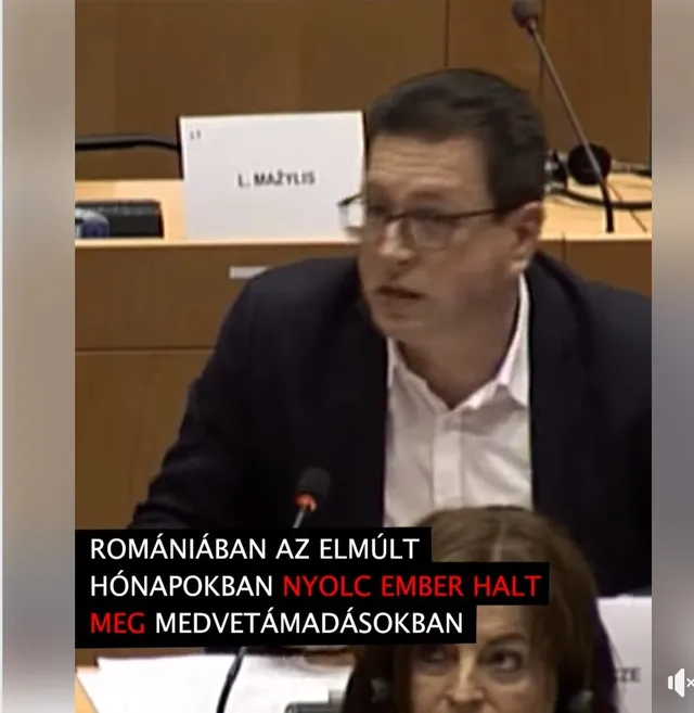Egy férfi felszólal az Európai Parlament üléstermében mikrofonba beszélve, előtte felirat: „Romániában az elmúlt hónapokban nyolc ember halt meg medvetámadásokban”. A háttérben egy másik résztvevő névtáblája (L. Mažylis) és mikrofonok láthatók, előtérben egy nő ül.